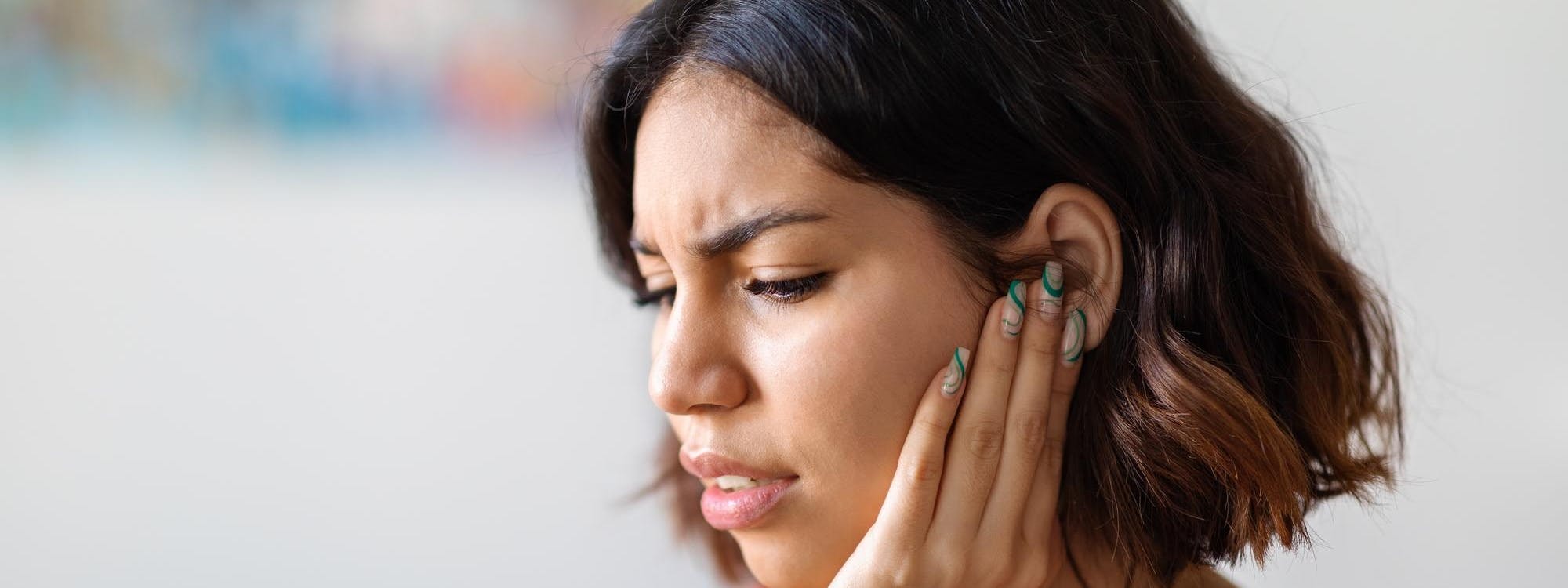 Frau mit Tinnitus hält Hand an das Ohr Frau mit Tinnitus hält Hand an das Ohr