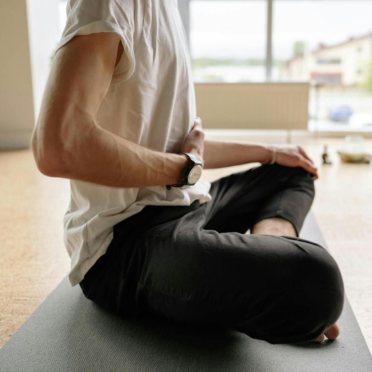 Mann im Schneidersitz macht Atemübung mit Hand auf dem Bauch