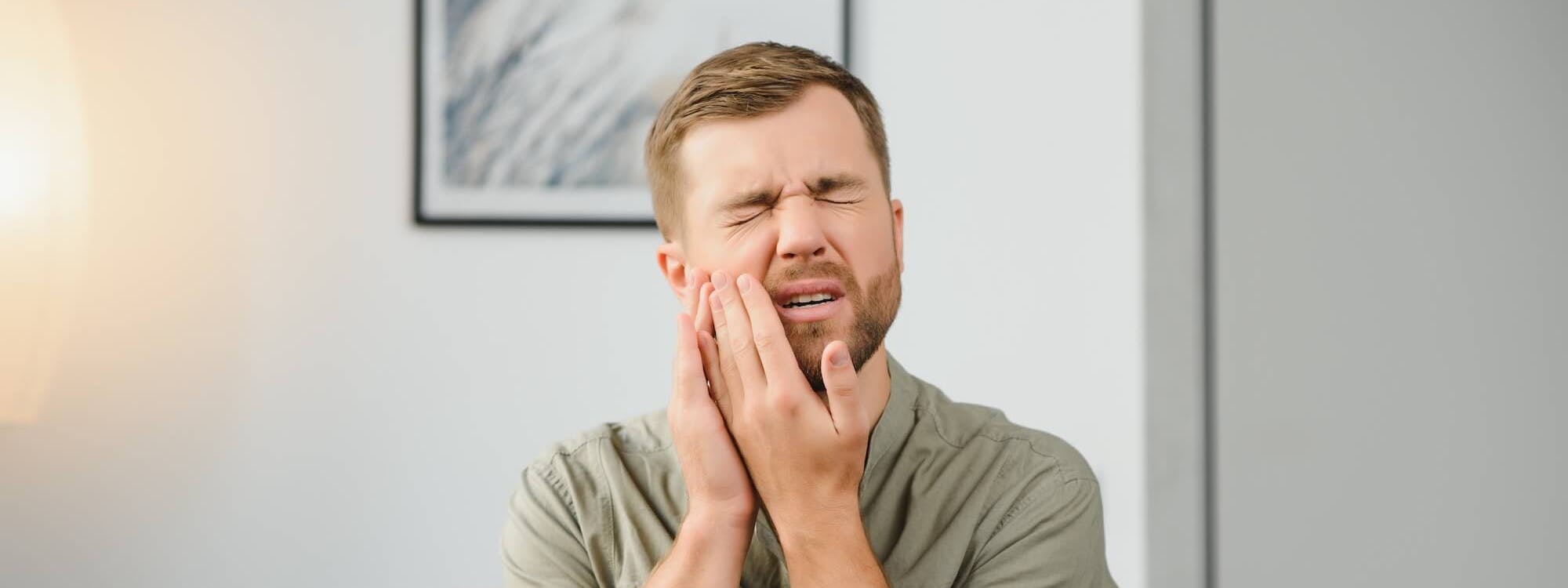 Mann hält Hand an schmerzendes Gesicht Mann hält Hand an schmerzendes Gesicht