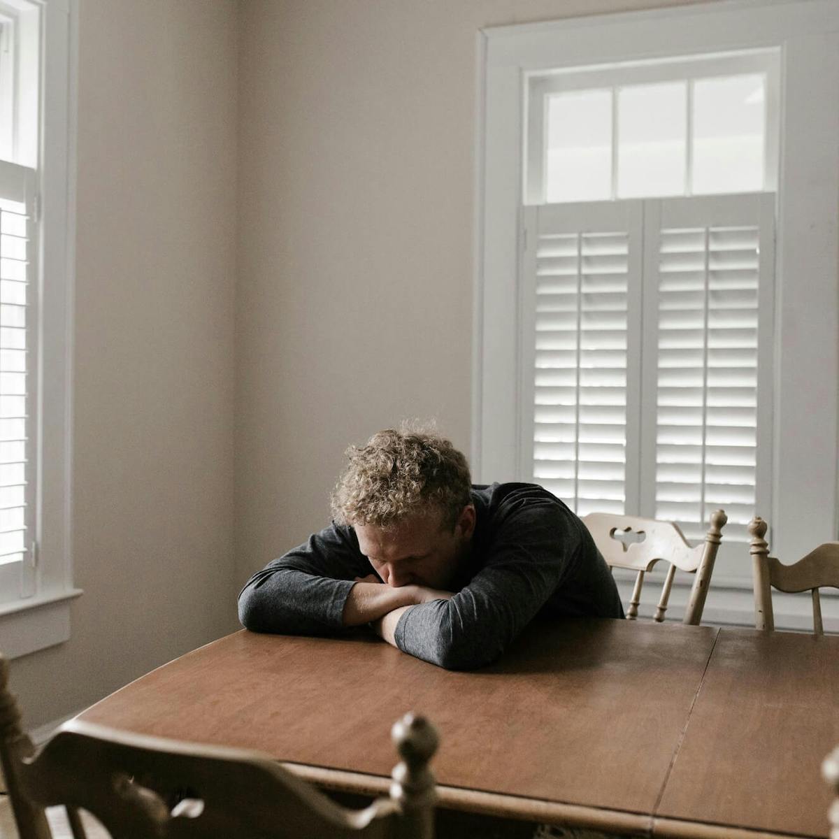 Mann lehnt sich traurig auf den Tisch