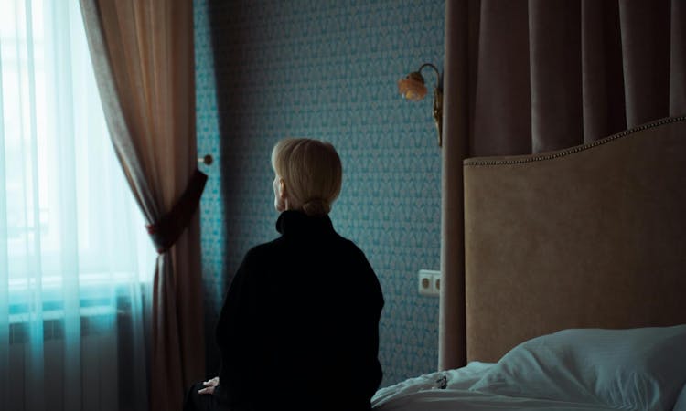 Frau sitzt traurig auf der Bettkante