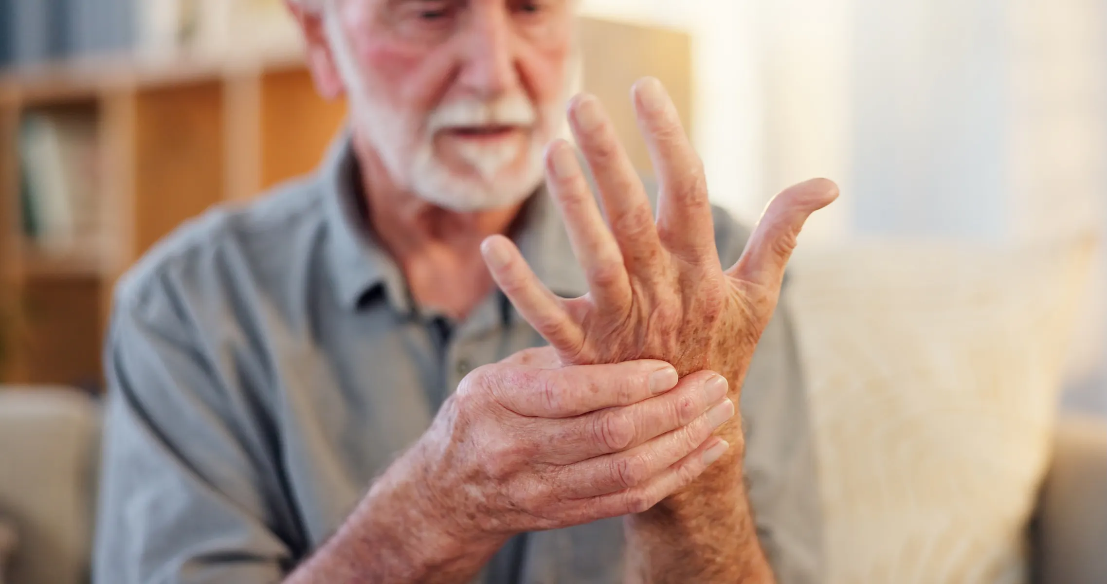 Alter Mann fasst sich an die eigene Hand