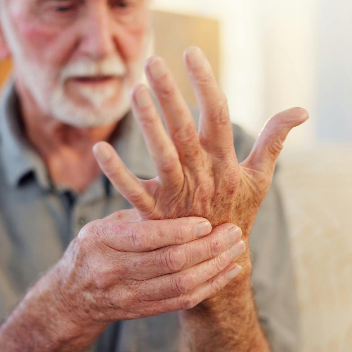 Älterer Mann fasst sich an die schmerzende Hand