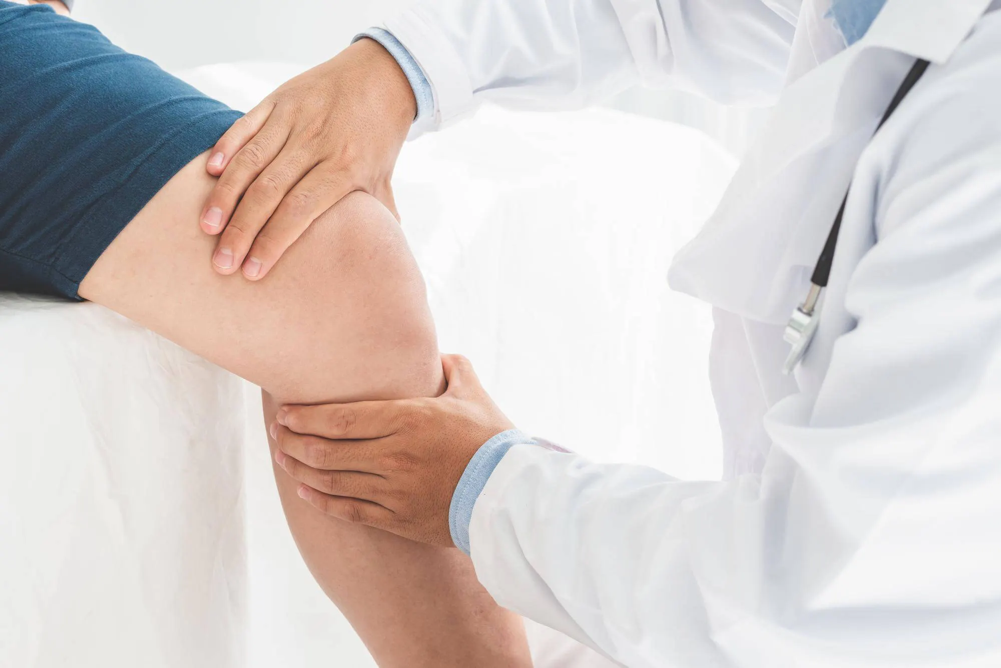 Arzt untersucht das Knie eines Patienten