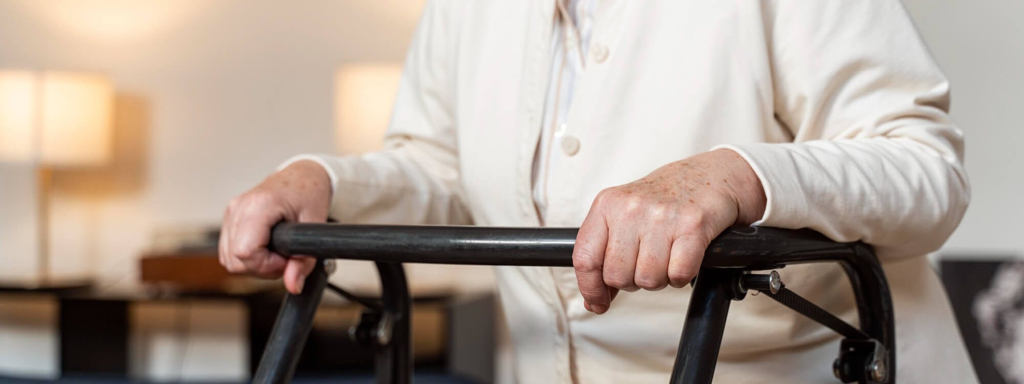 Ältere Frau mit Multipler Sklerose hält sich an Gehgestell fest