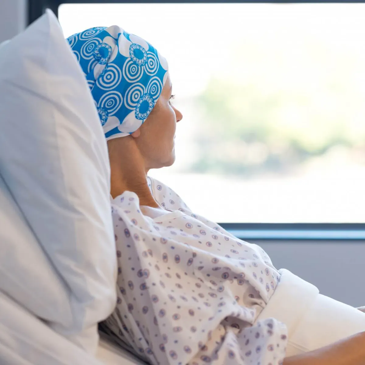 Krebspatientin sitzt im Krankenhausbett und schaut aus dem Fenster