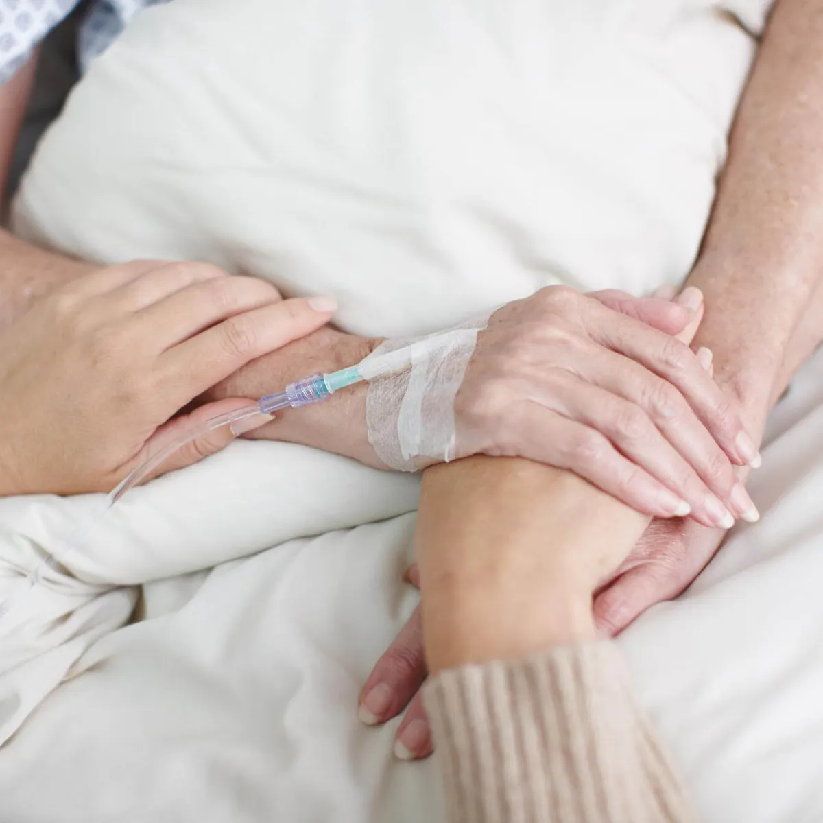 Angehörige hält die Hände einer an Bauchspeicheldrüsenkrebs erkrankten Person