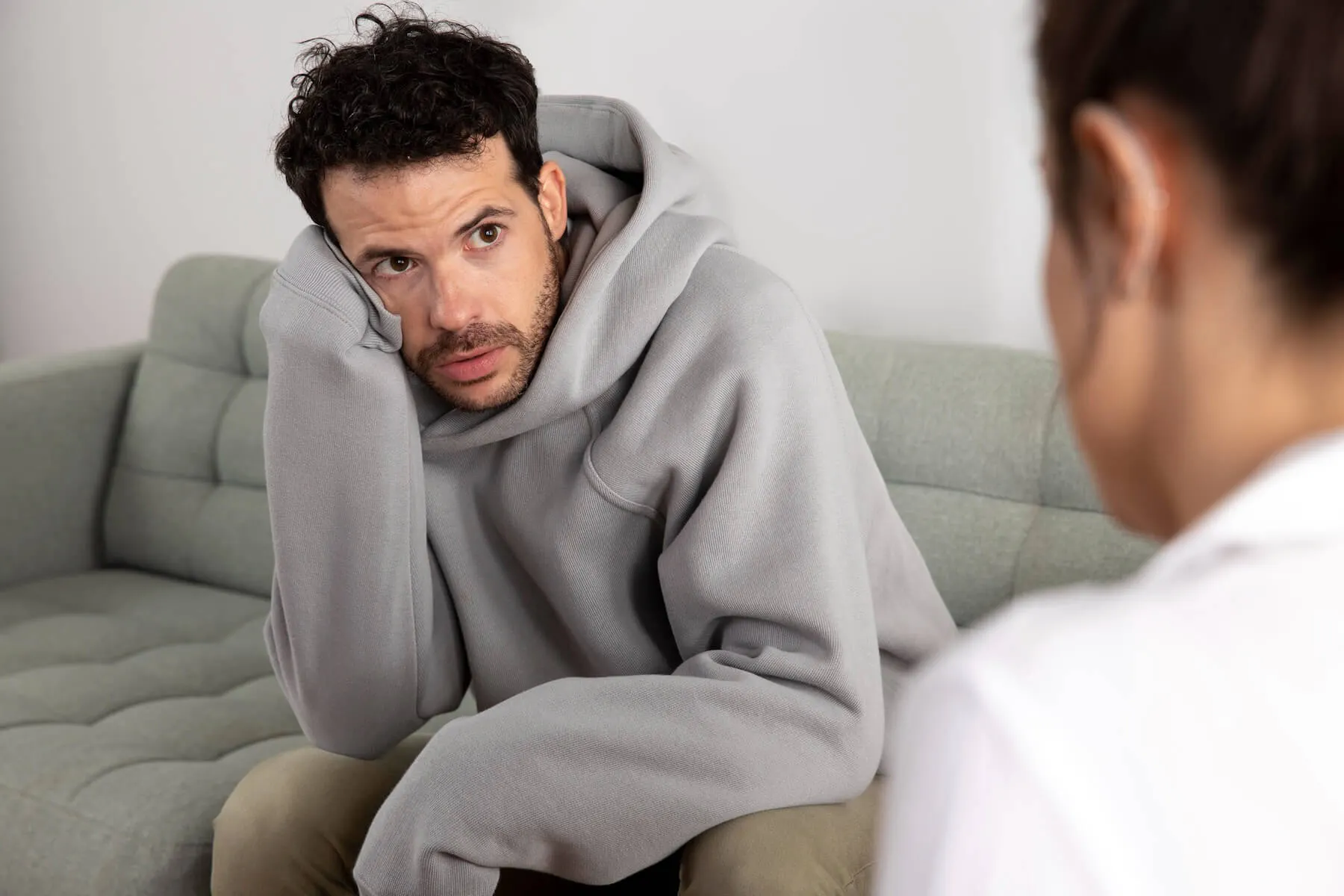 Mann sitzt traurig auf dem Sofa und schaut zu einer anderen Person