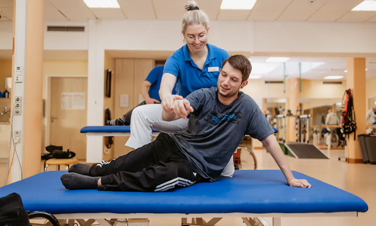 Physiotherapeutische Behandlung querschnittgelähmter Patient auf Liege mit Physiotherapeutin