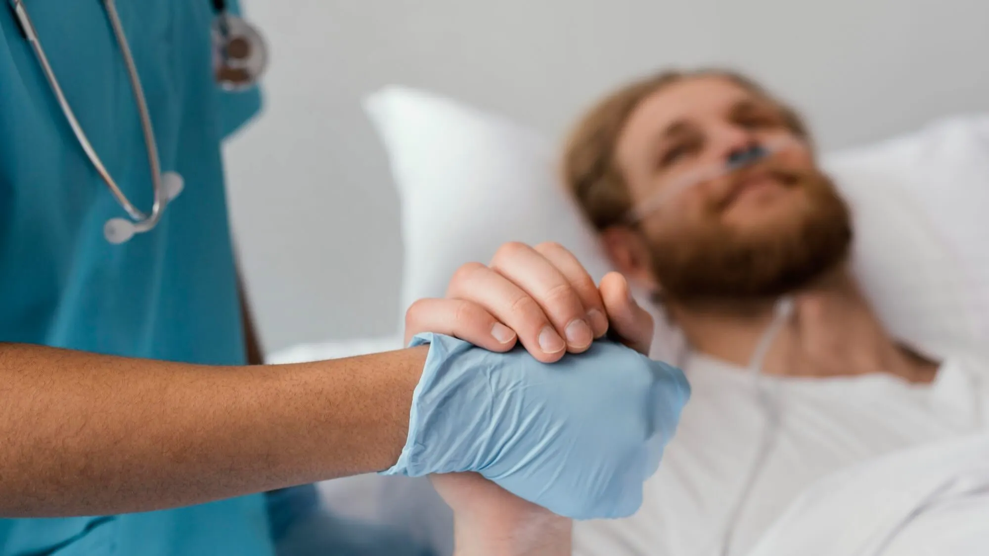 Männlicher Patient hält Hand einer Pflegeperson