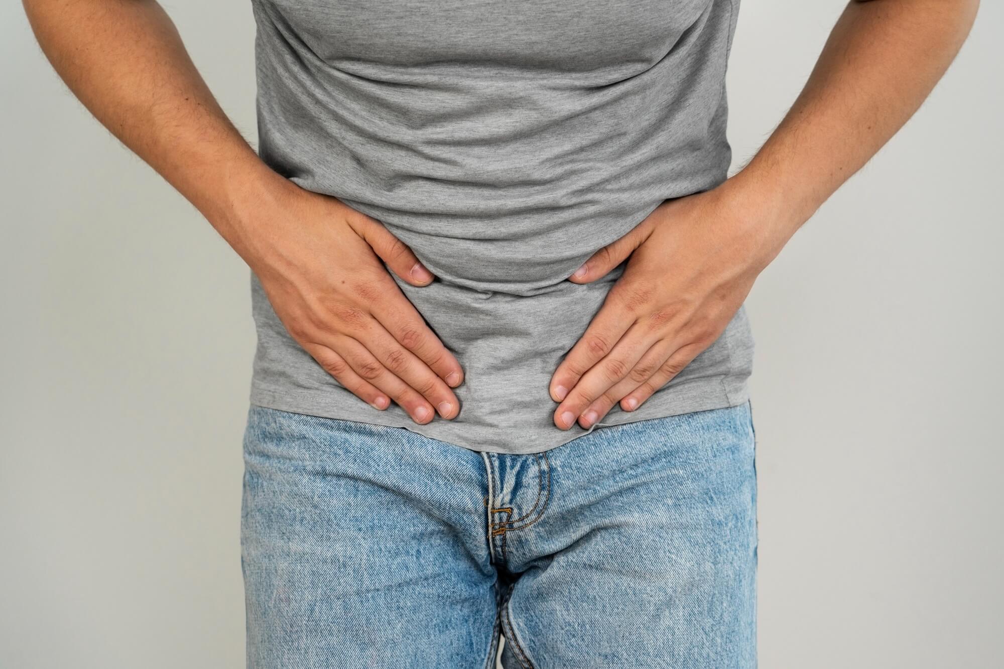 Mann hält seine Hände vor seinen Unterbauch