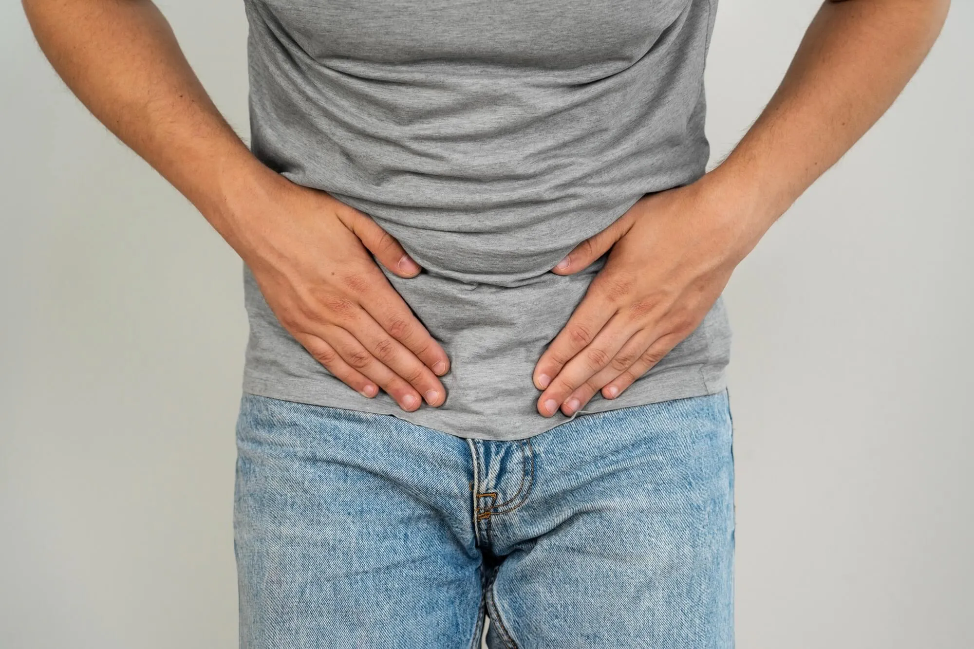 Mann hält sich die Hände an den Unterbauch