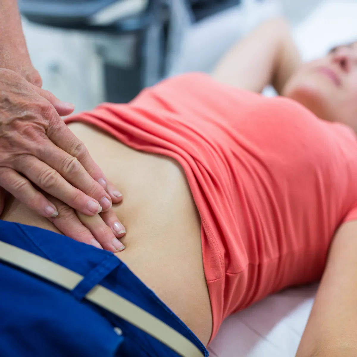 Hände drücken auf den Bauch einer Patientin