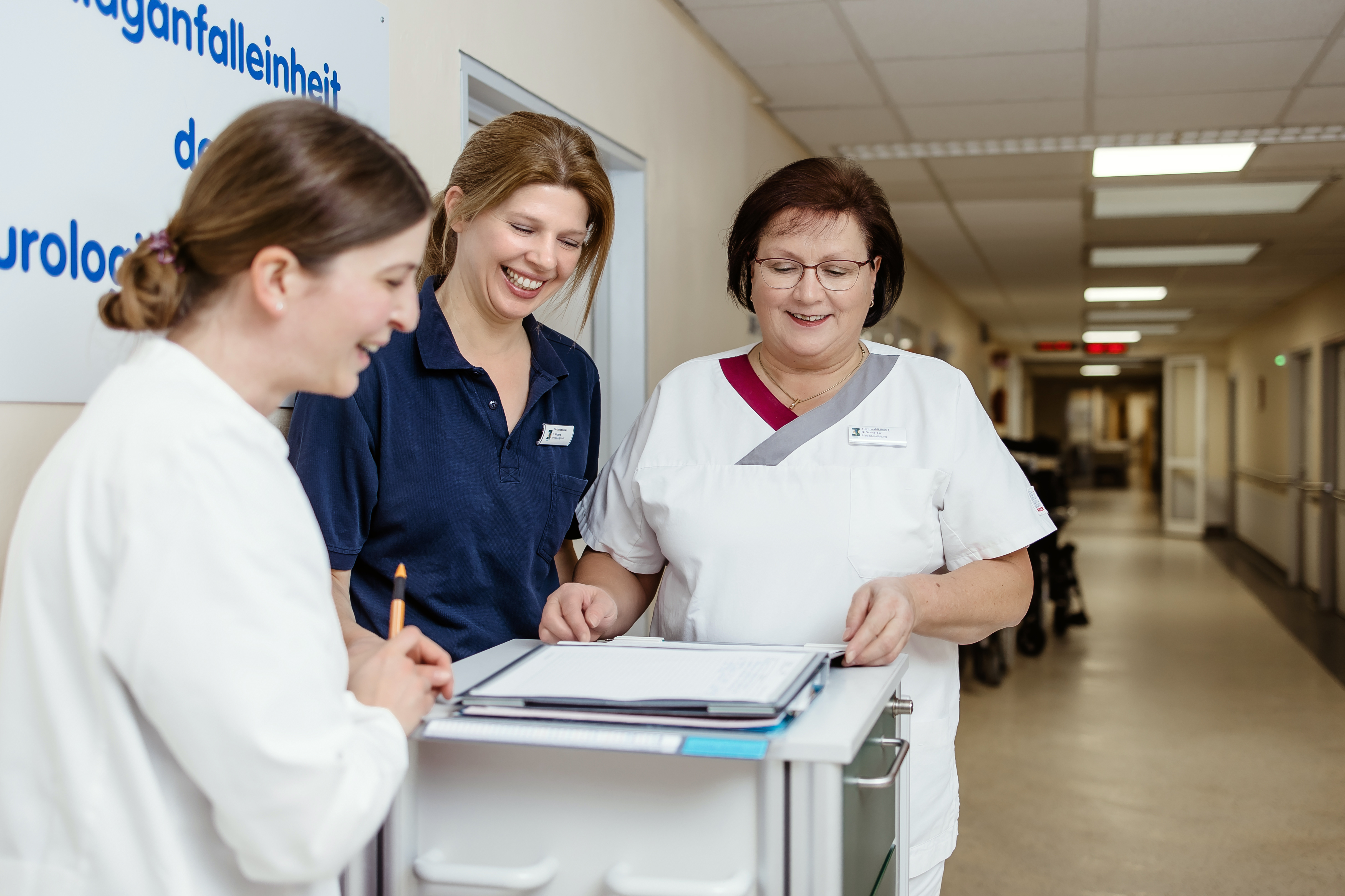 Drei Mitarbeiterinnen des neurologischen Zentrums unterhalten sich im Krankenhausflur