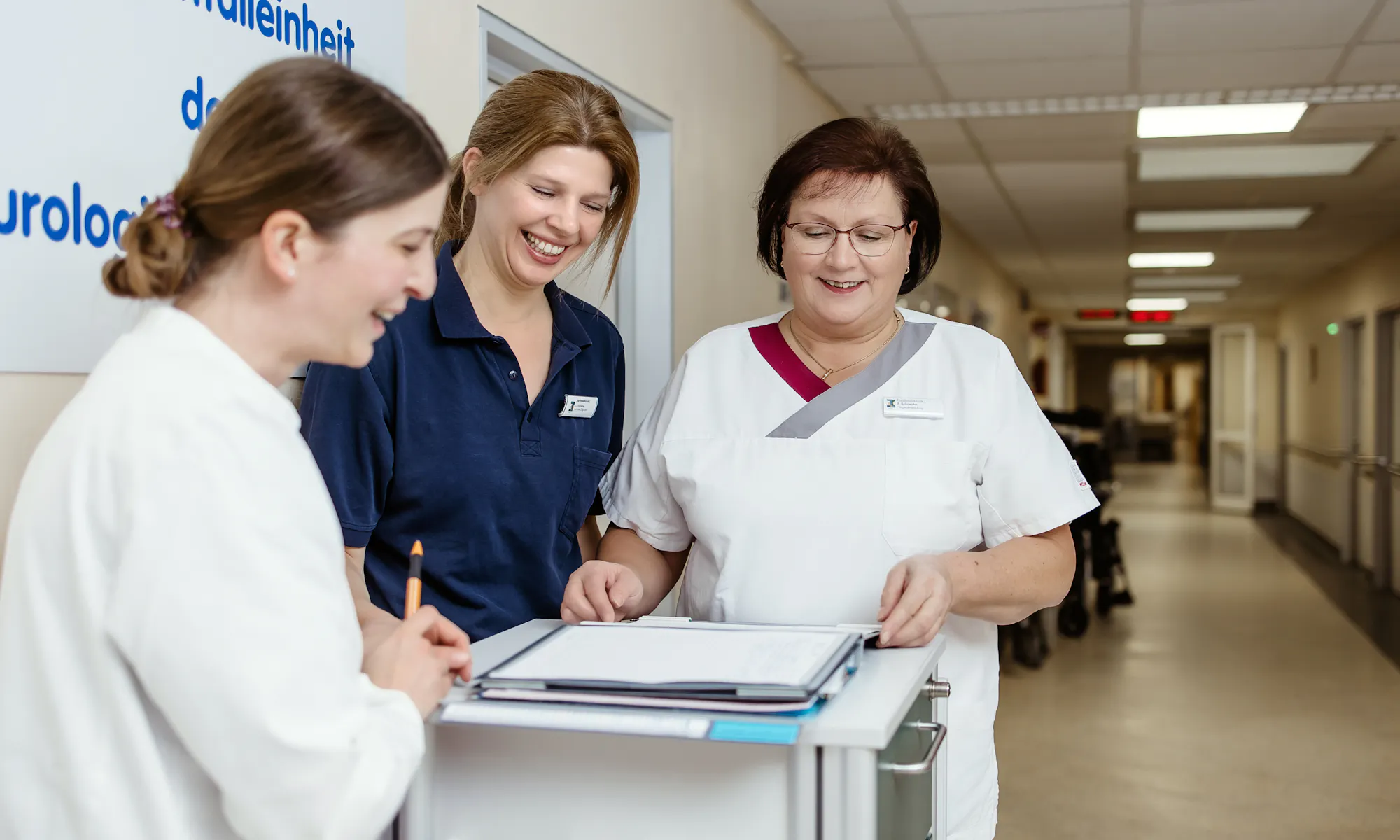 Drei Mitarbeiterinnen des neurologischen Zentrums unterhalten sich im Krankenhausflur