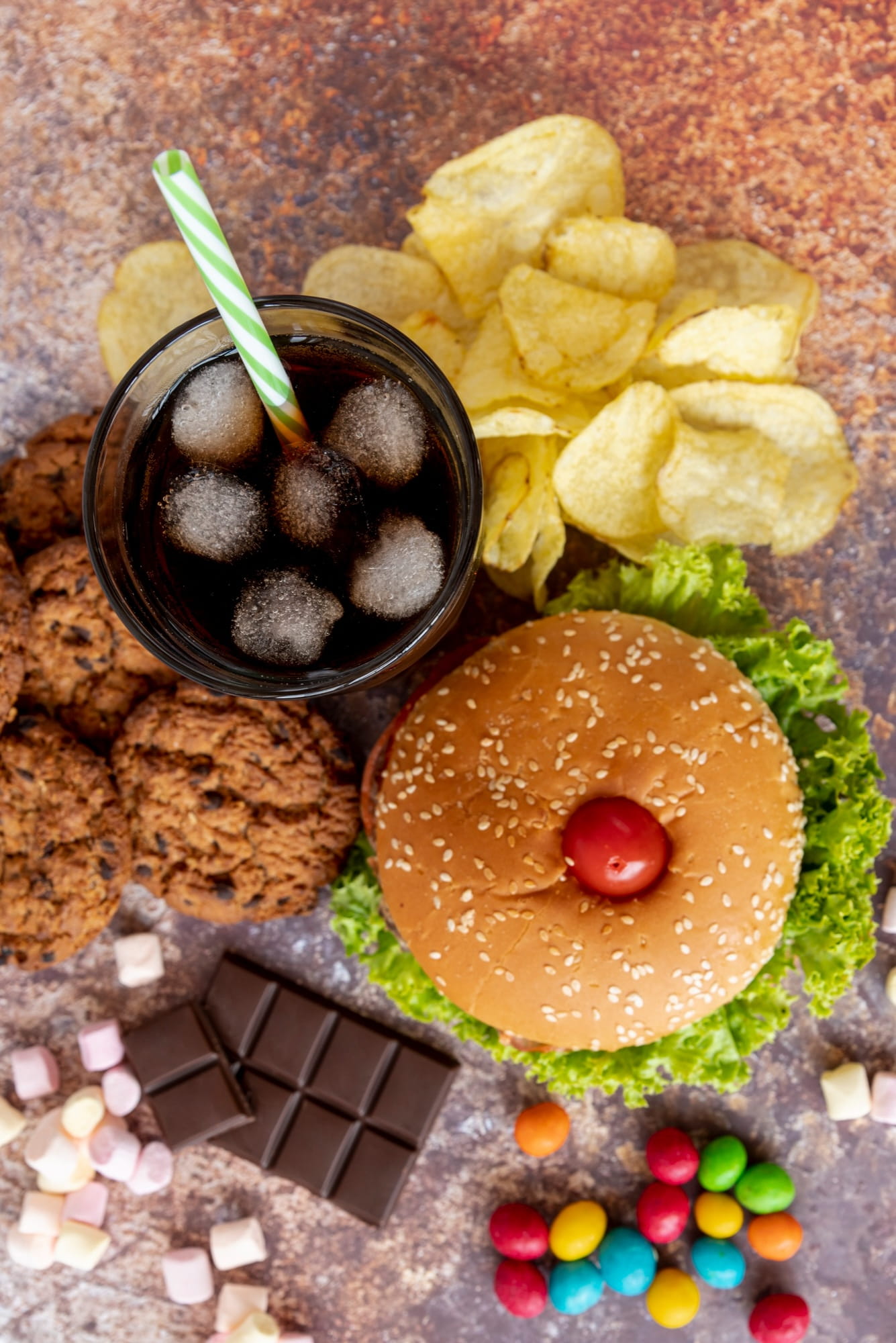 Ungesunde Lebensmittel wie Burger und Süßigkeiten liegen nebeneinader auf einem Tisch