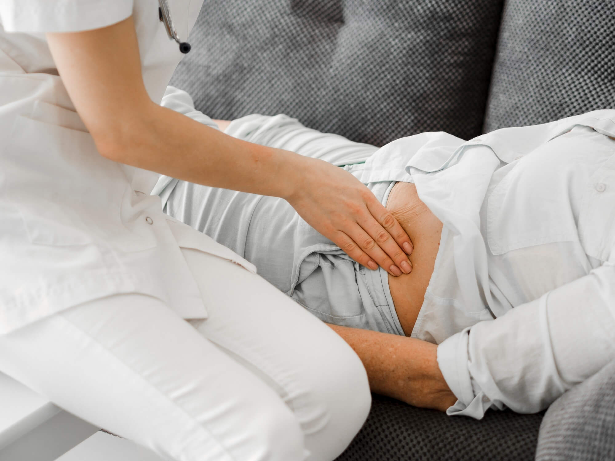 Ärztin tastet den Bauch eines Patienten ab