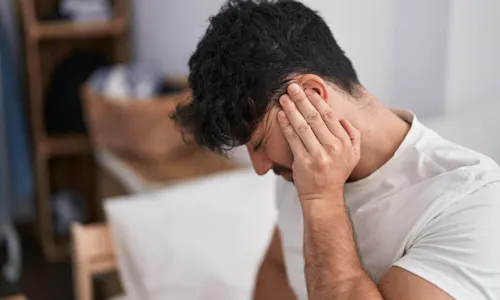 Mann mit chronischem Tinnitus hält sich mit schmerzverzerrtem Gesicht eine Hand ans Ohr