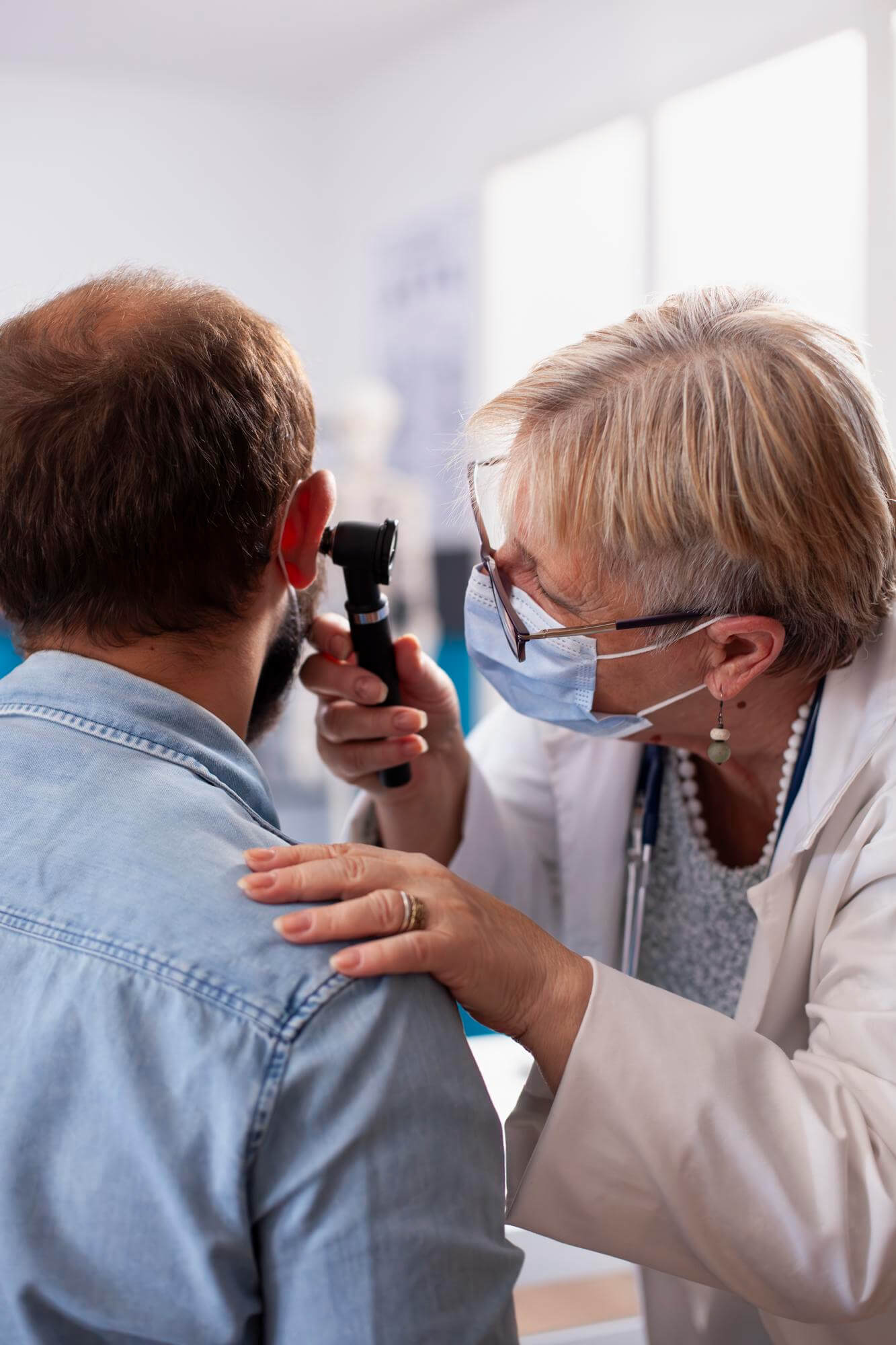 Patient mit chronischem Tinnitus wird von Ärztin am Ohr untersucht