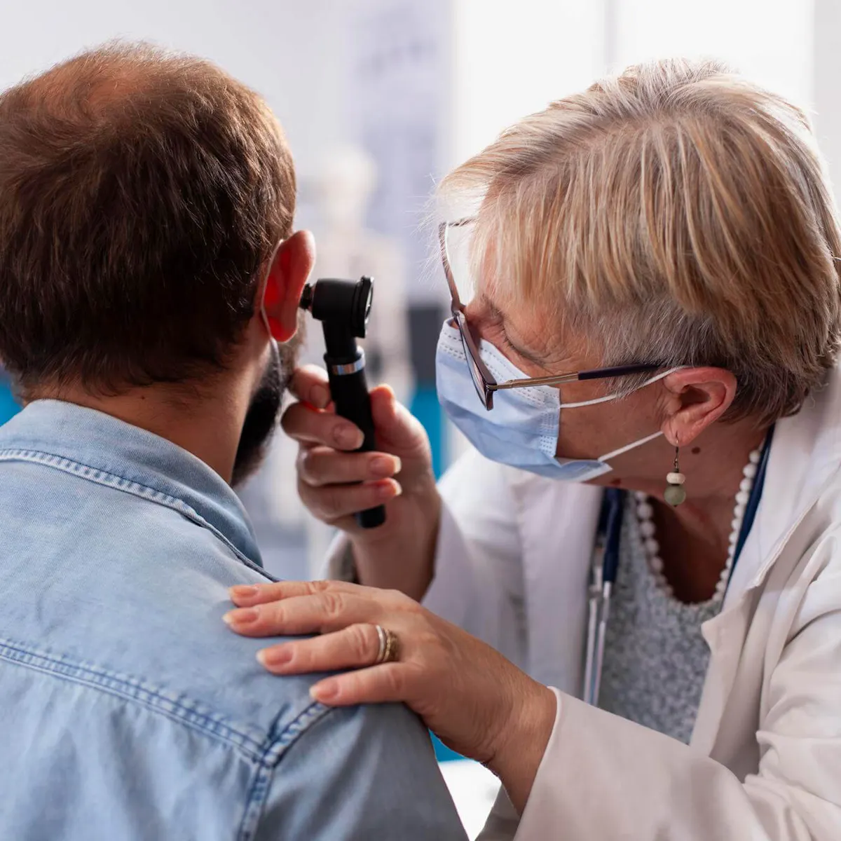 Patient mit chronischem Tinnitus wird von Ärztin am Ohr untersucht