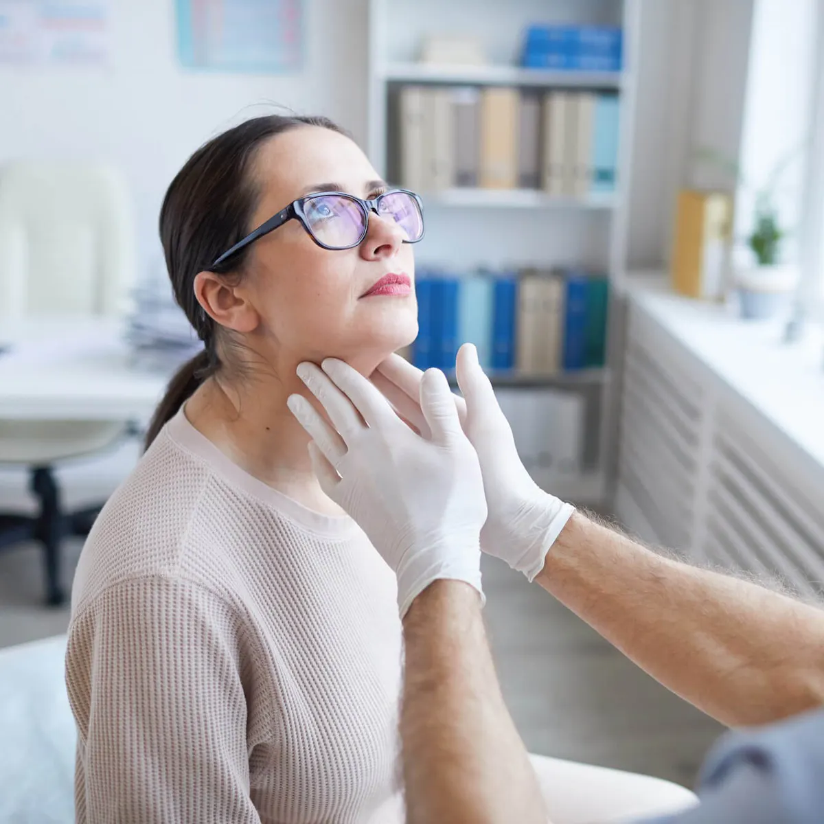 Arzt tastet den Hals einer Patientin ab