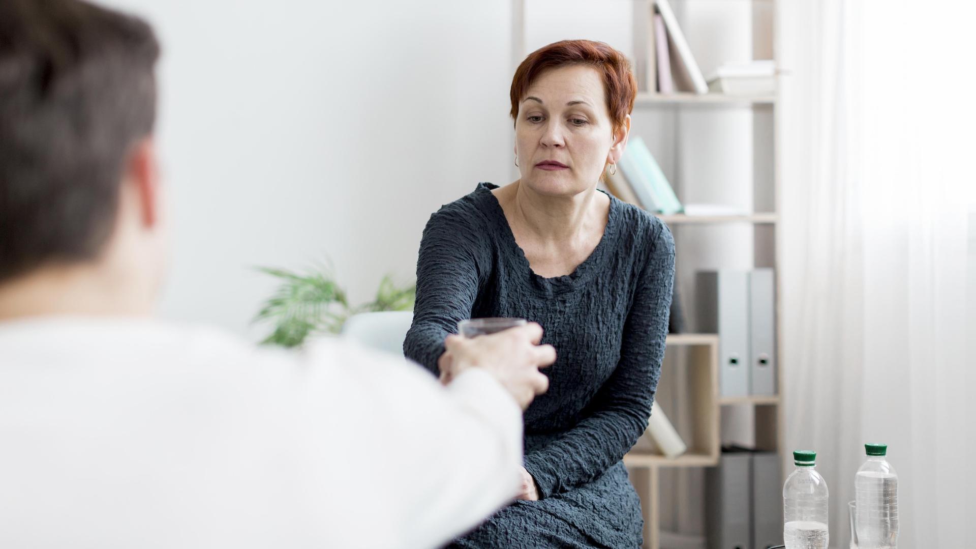 Frau im Gespräch mit einem Therapeuten bei der Behandlung einer psychosomatischen Funktionsstörung