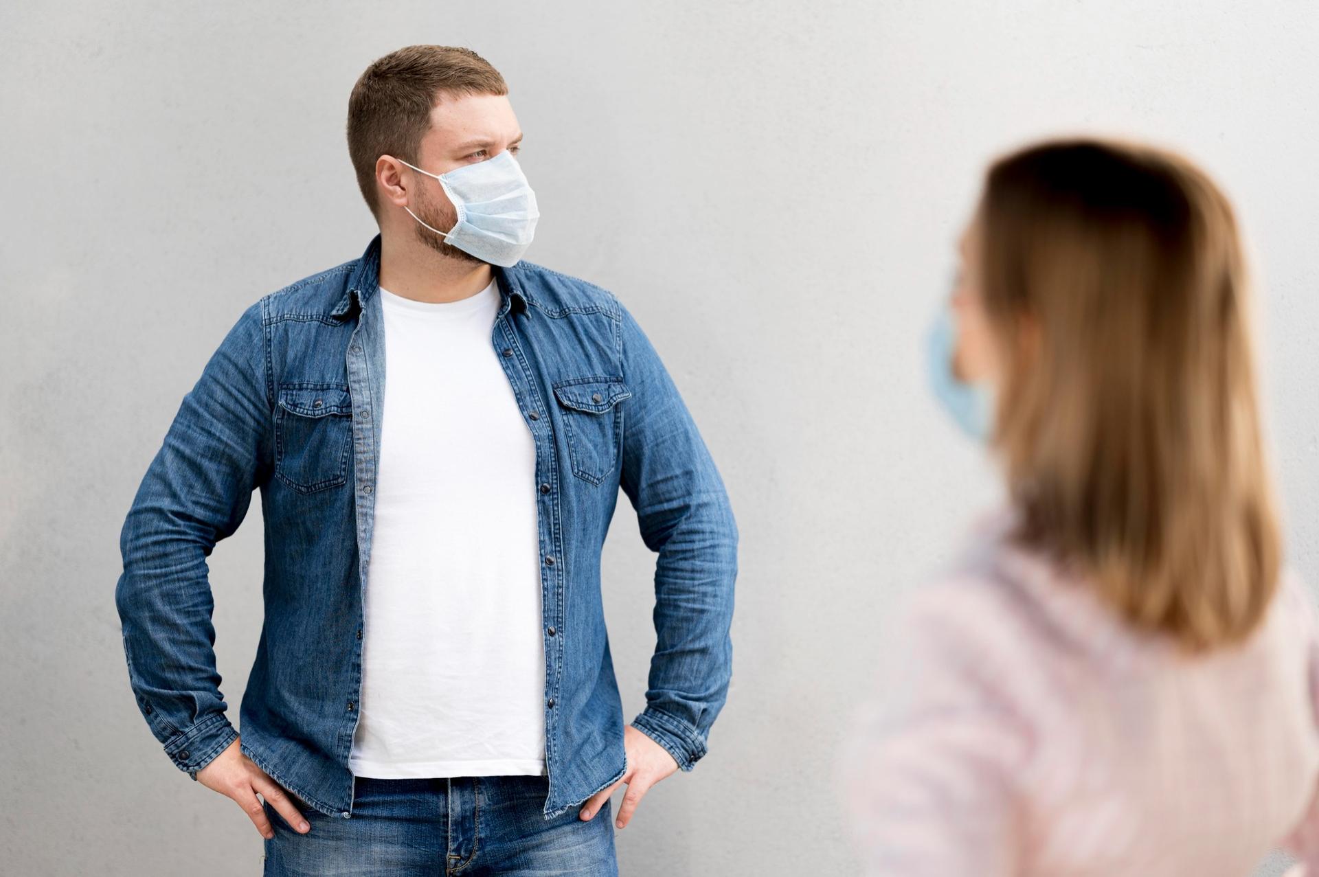 Mann und Frau mit Atemschutzmasken stehen sich gegenüber