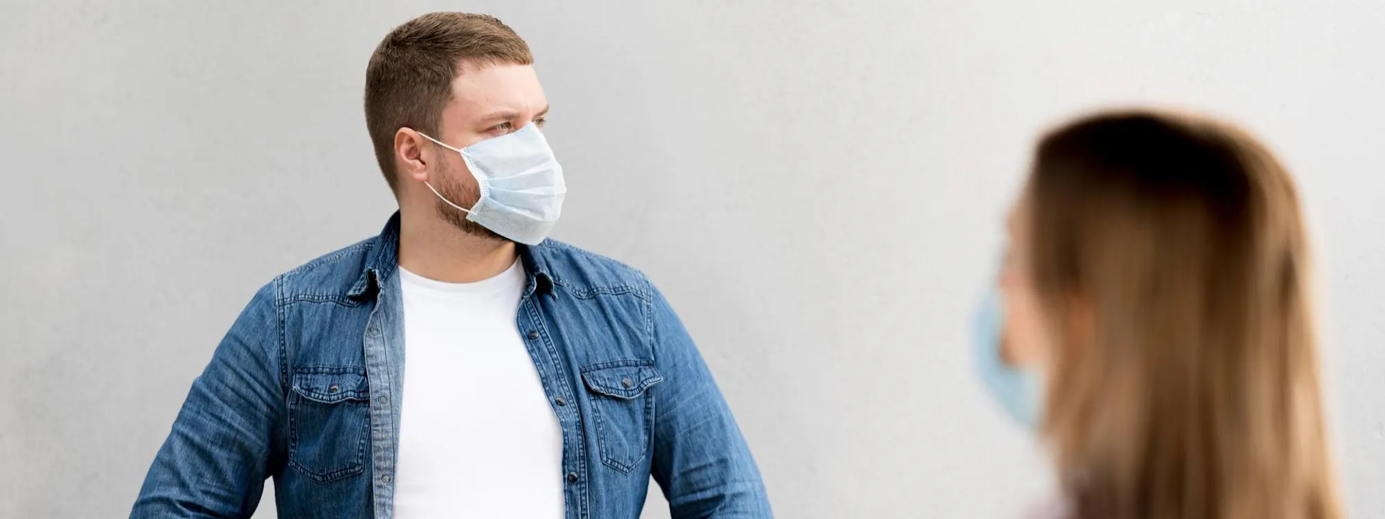 Mann und Frau mit Atemschutzmasken stehen sich gegenüber