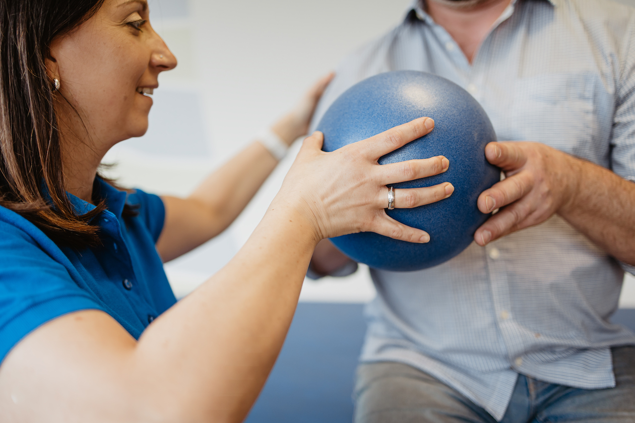 Patientin mit neuromuskulärer Erkrankung hält Ball bei der Physiotherapie