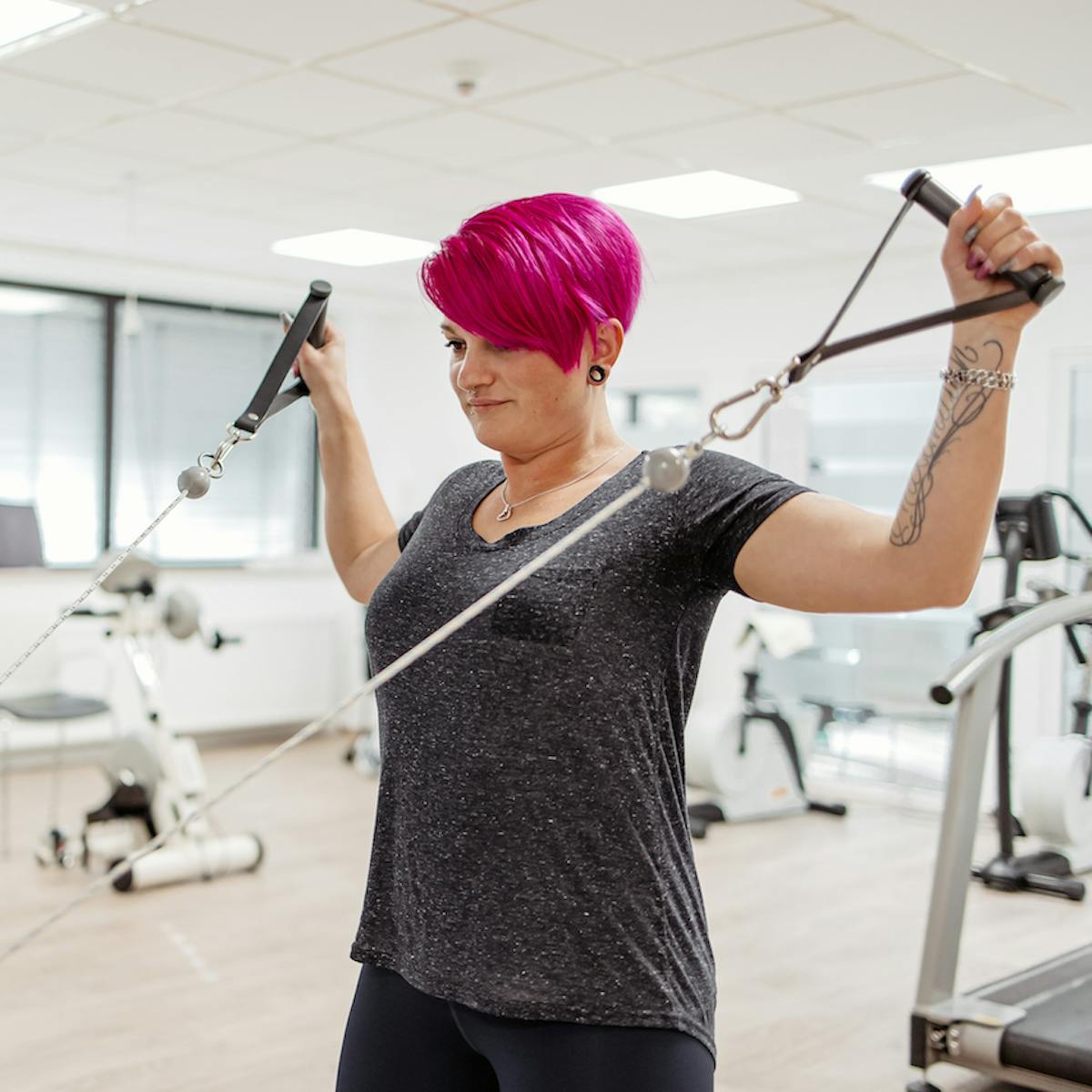 Patientin macht eine Kraftübung am Gerät bei der Physiotherapie