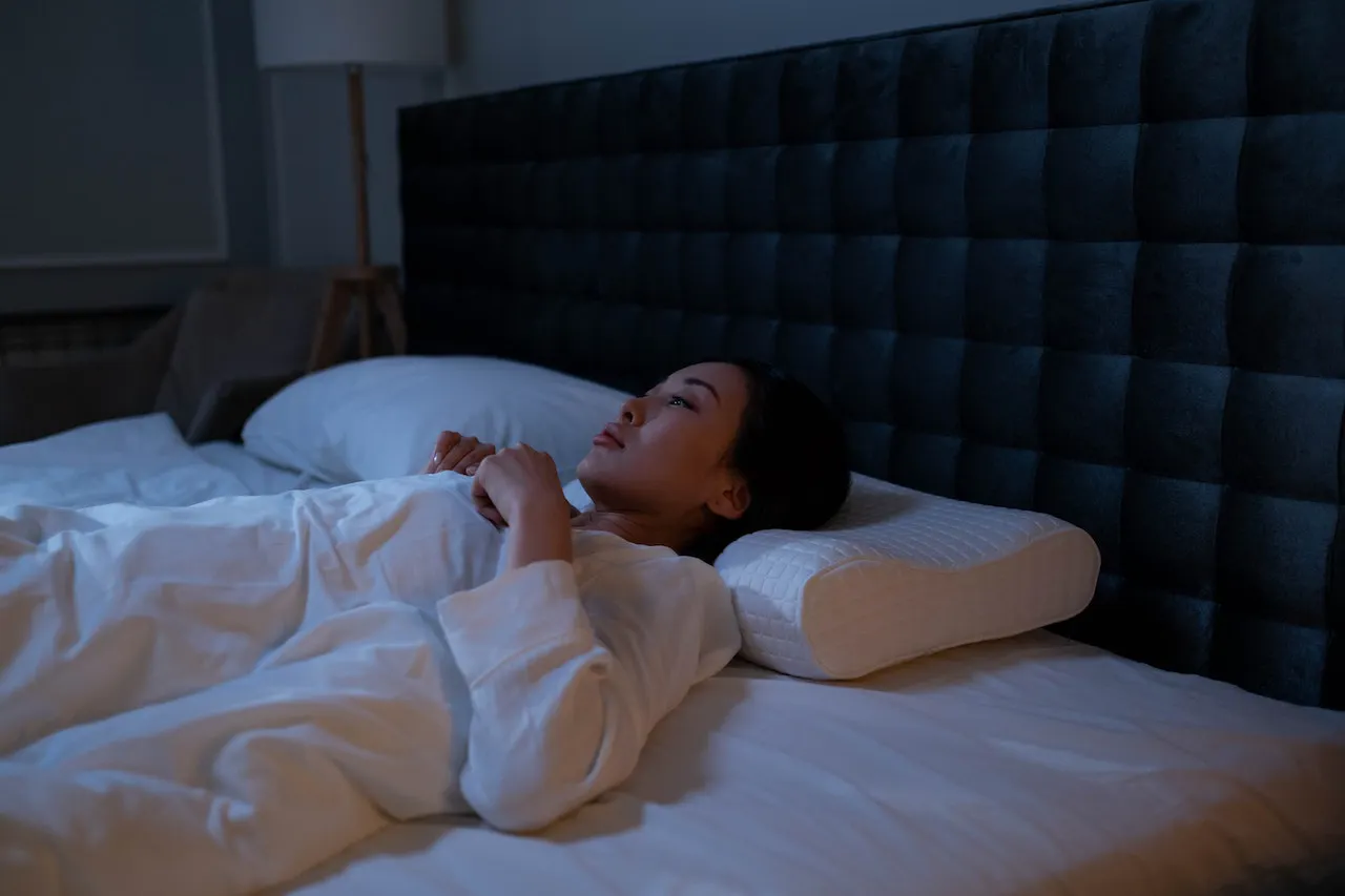 Frau liegt auf dem Rücken im Bett und schläft