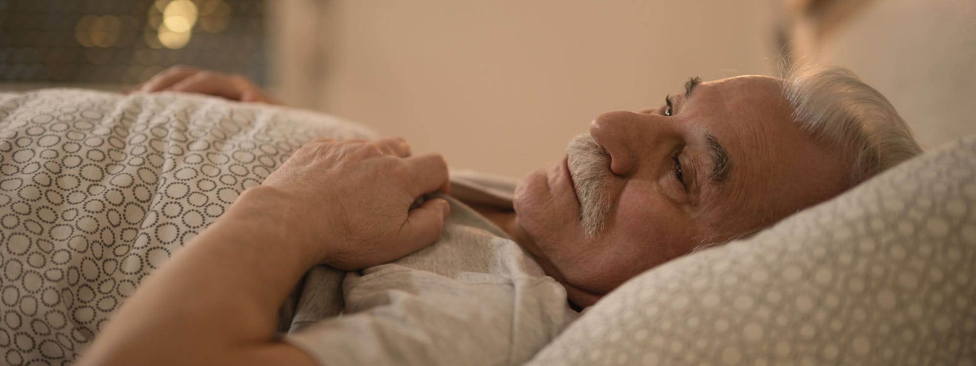 Älterer Mann liegt müde im Bett