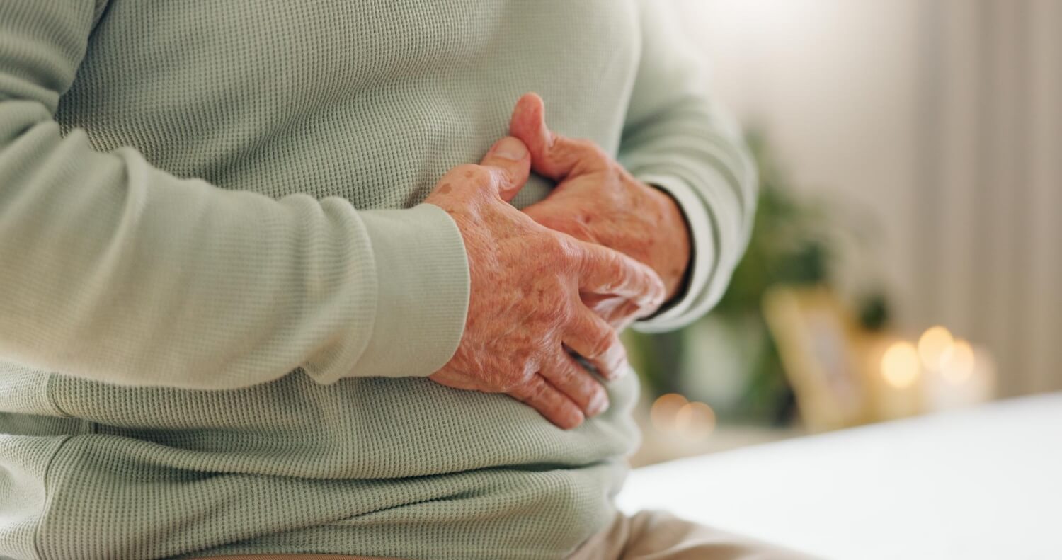 Älterer Mann hält sich die Hände an den Bauch