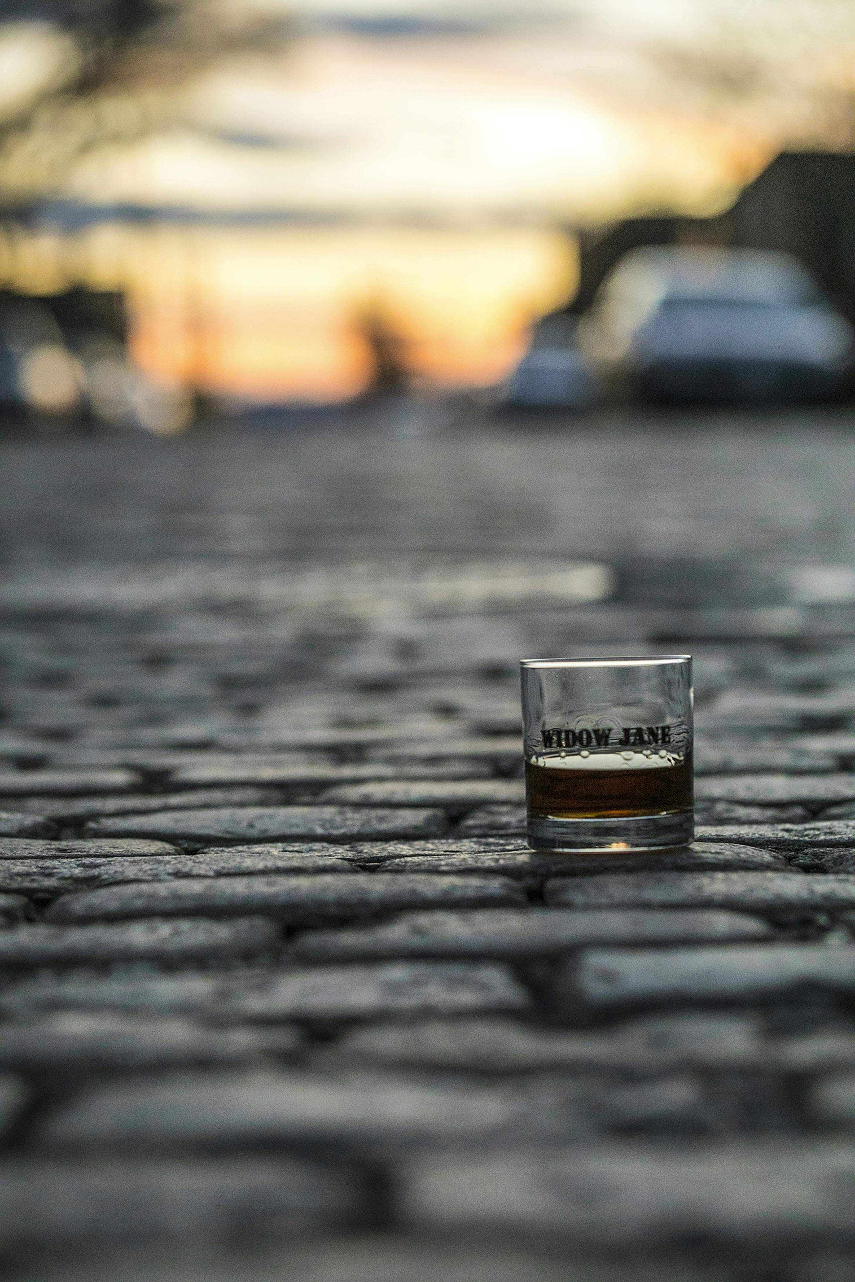 A glass of whiskey on a cobblestone street