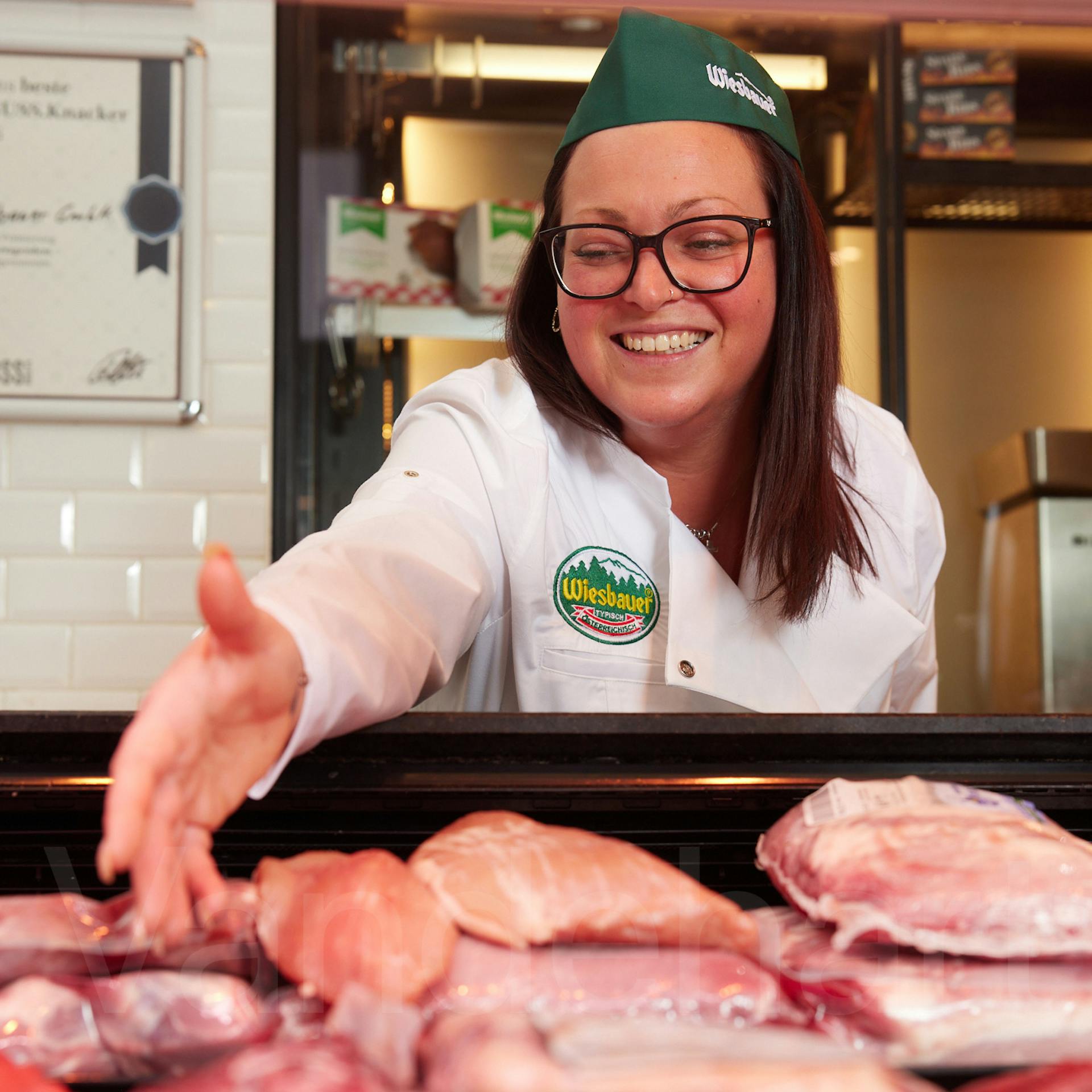 Eine Fachverkäuferin von Wiesbauer berät Kunden an der Fleisch- und Wursttheke.