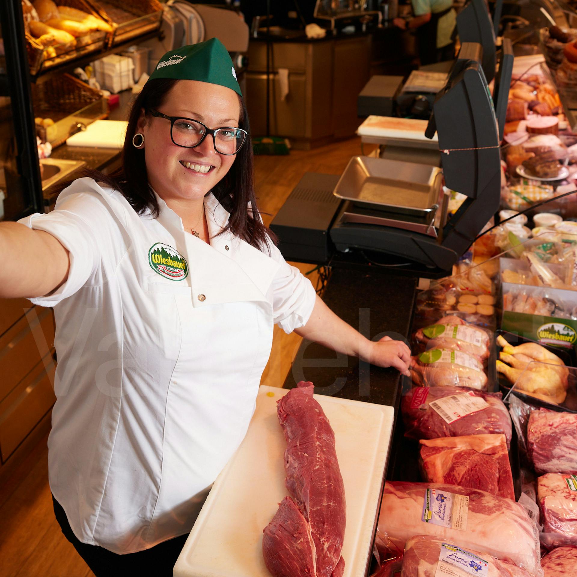 Eine Fachverkäuferin von Wiesbauer berät Kunden an der Fleisch- und Wursttheke.