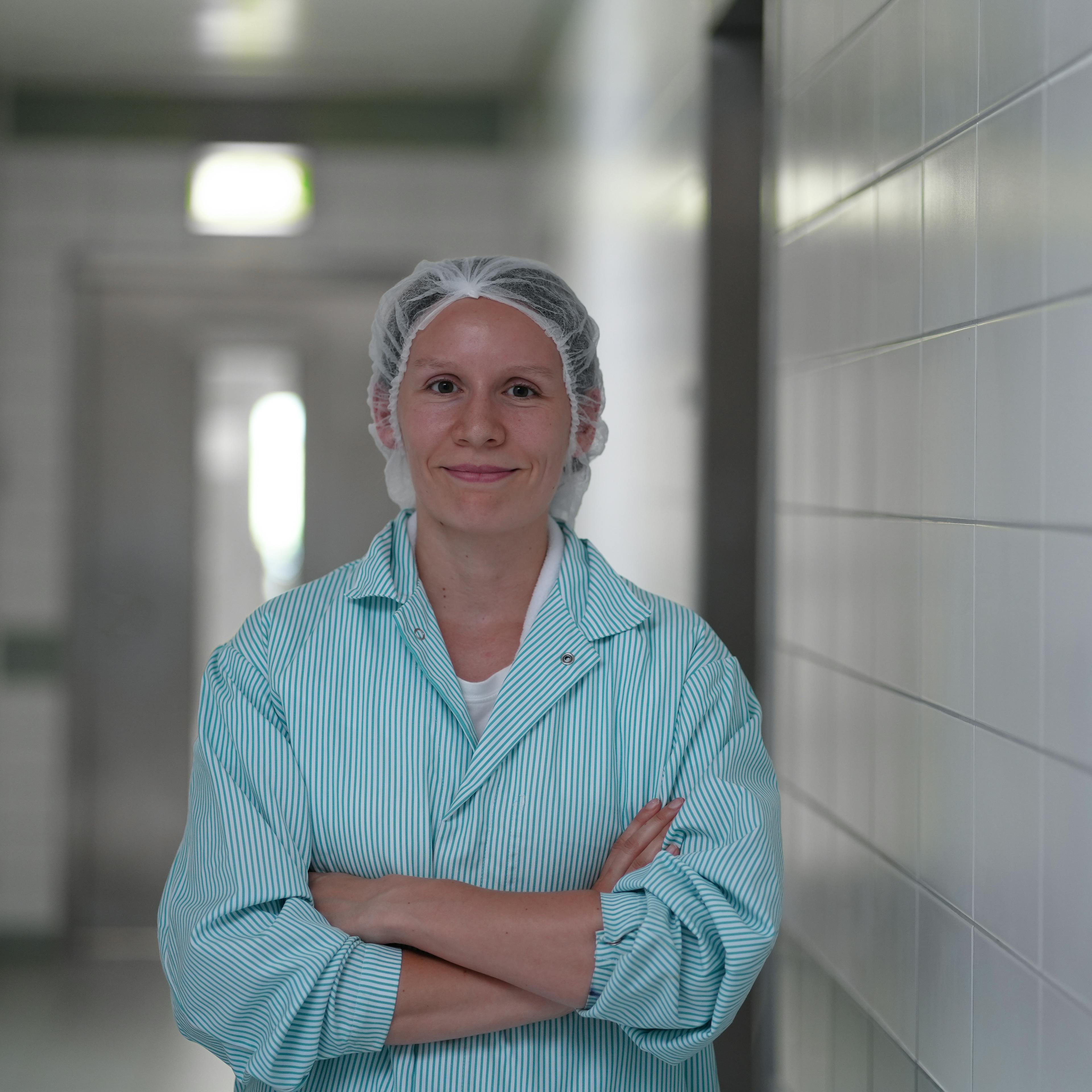 Eine Mitarbeiterin schaut lächelnd mit verschränkten Armen in die Kamera