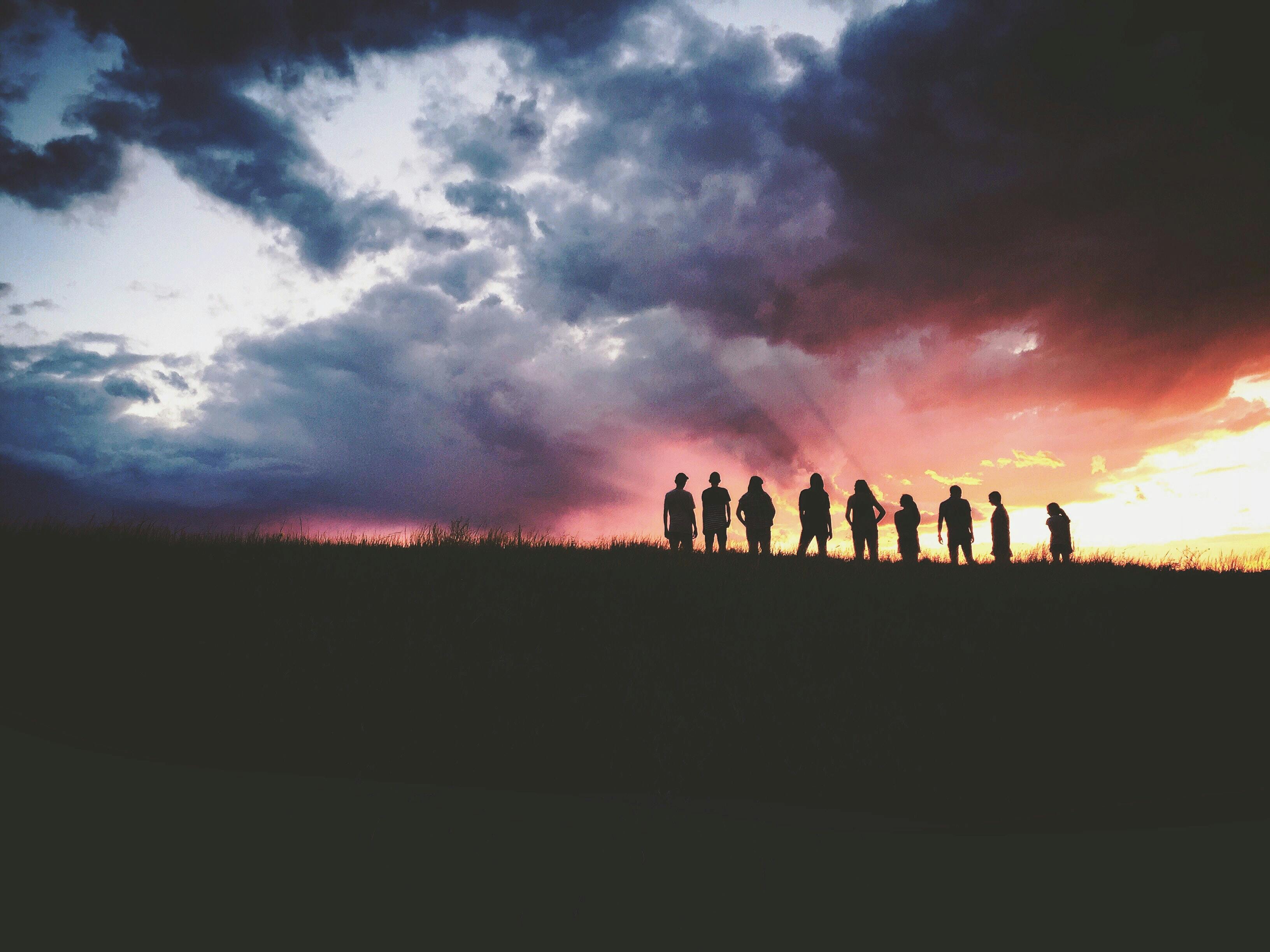 silhouette of people on a hill at dusk