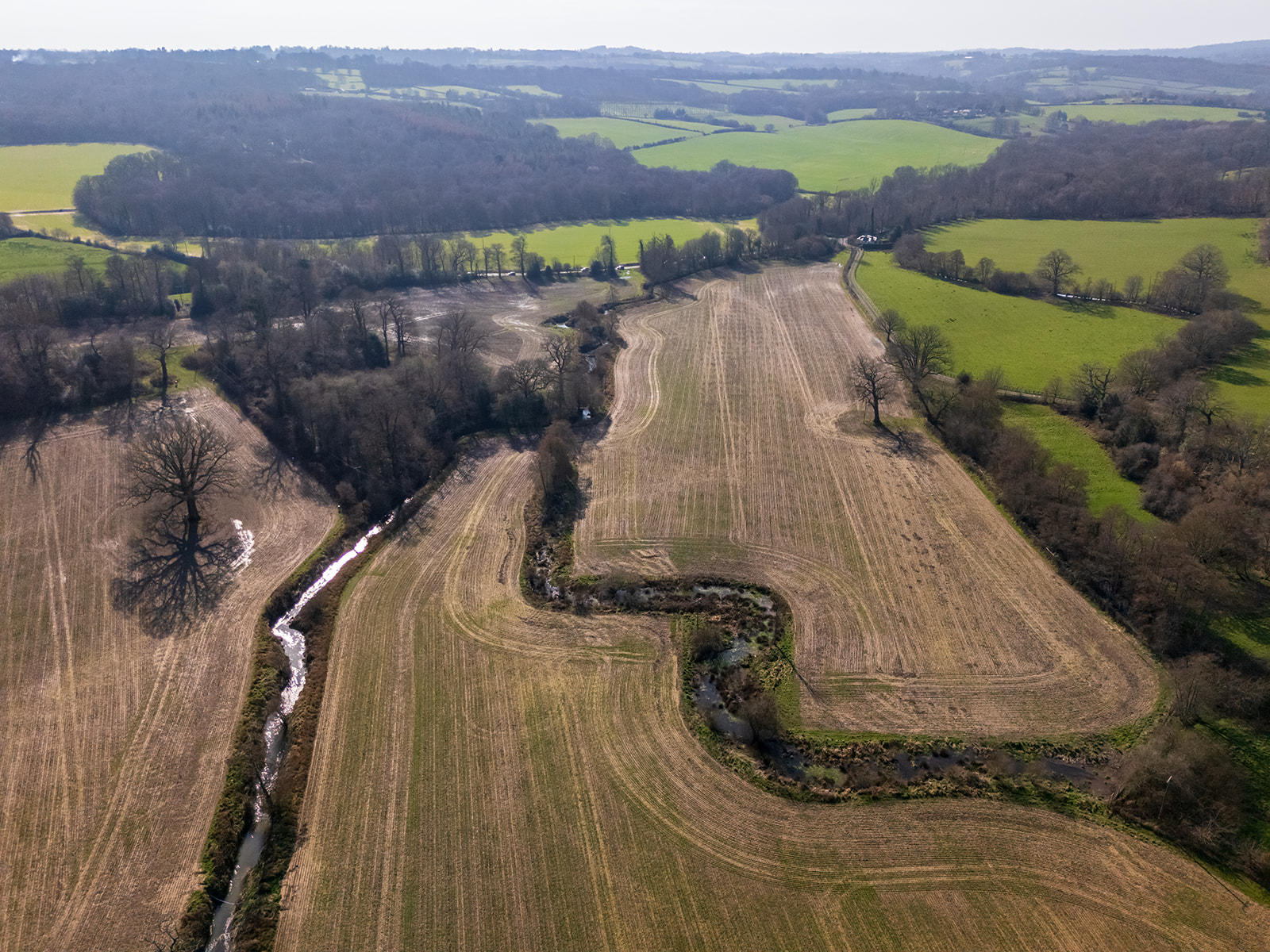 drone shot of farmland with stream running through it