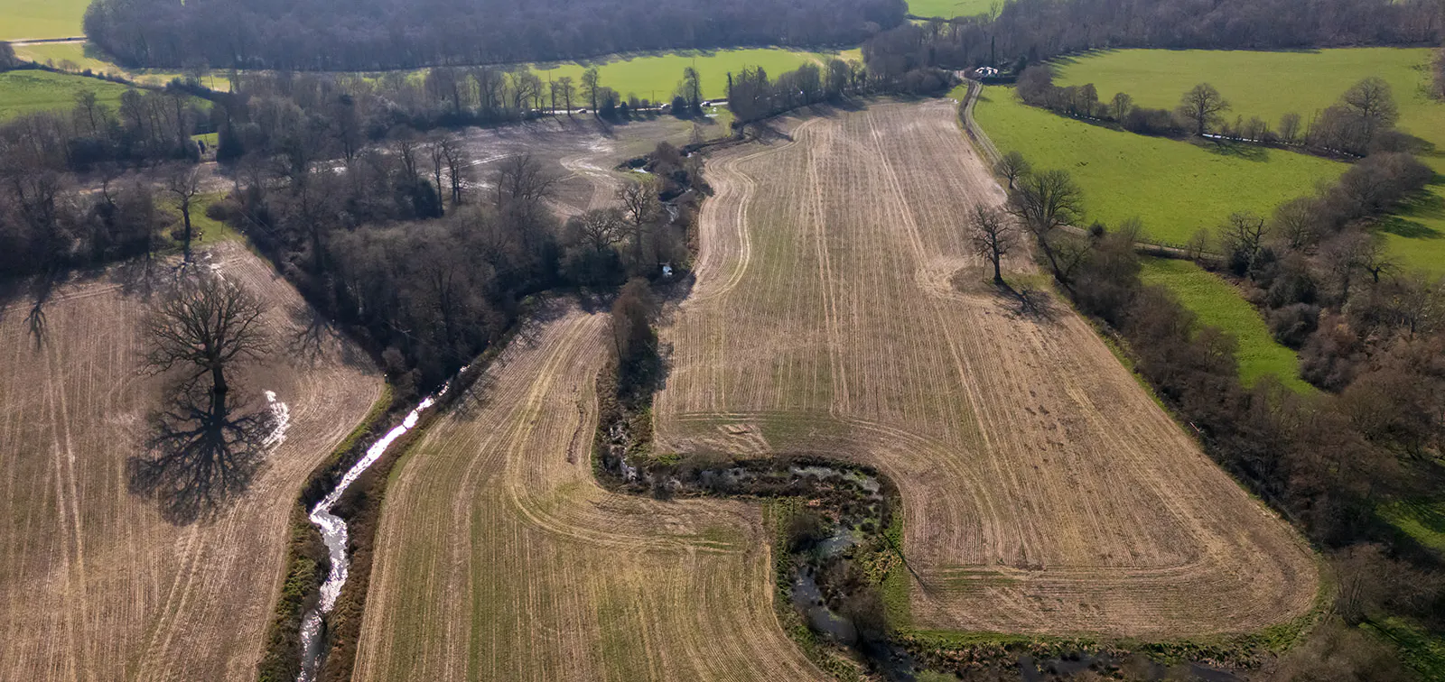 drone shot of farmland with stream running through it