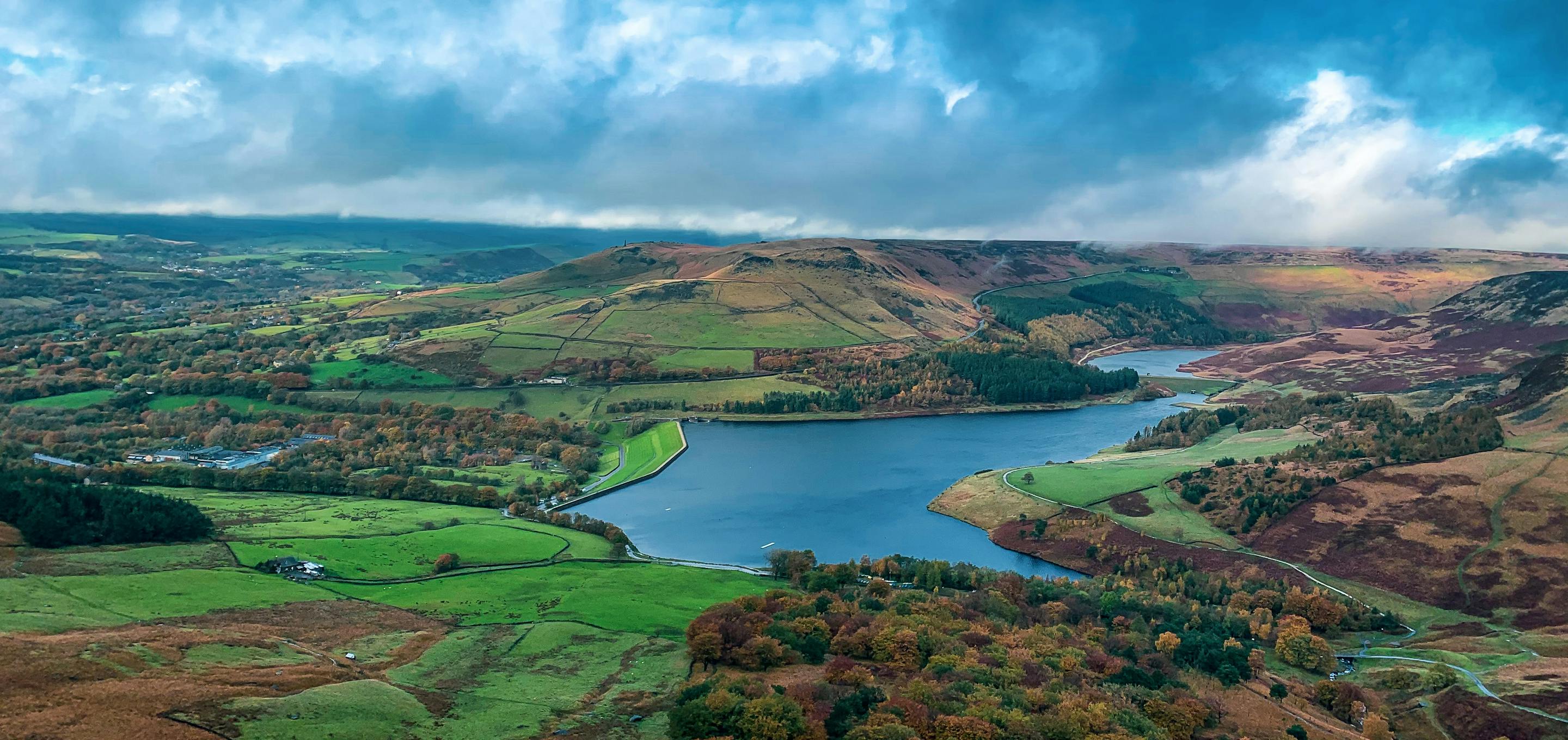 A hilltop view of a lake surrounded by green fields