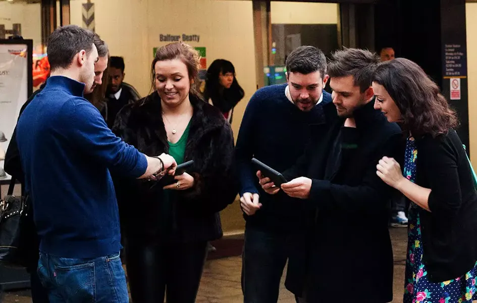 Group of people standing outside, looking at their tablets