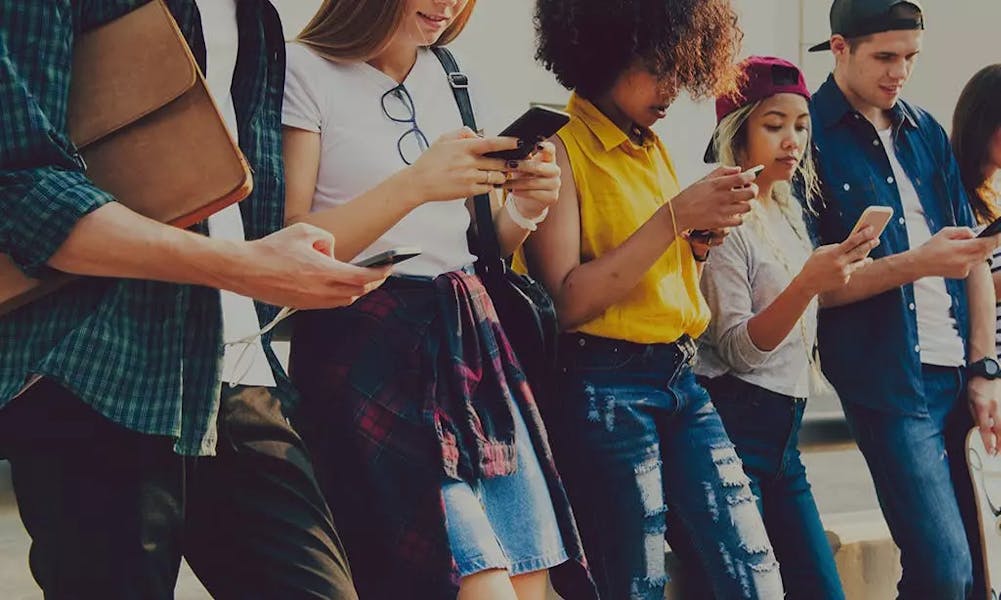 A line of young people using their mobile phones