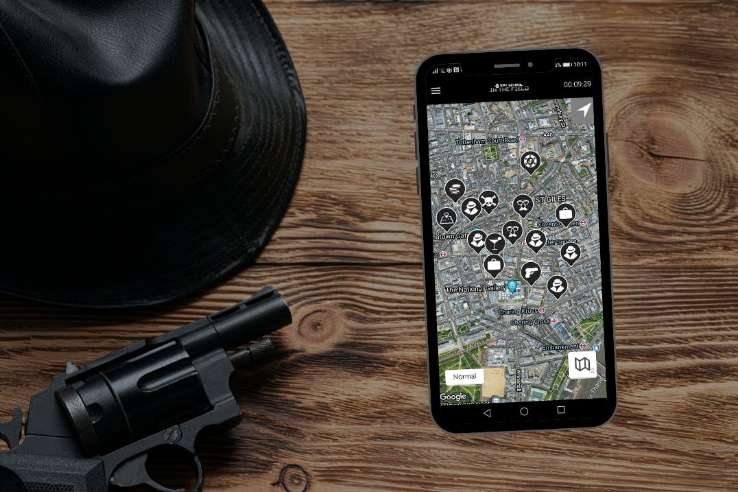 Spy hat, mobile phone and gun on wooden desk