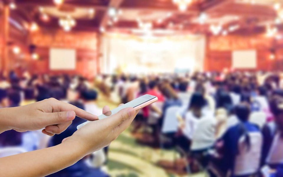 Close up of a mobile phone user in a busy conference event