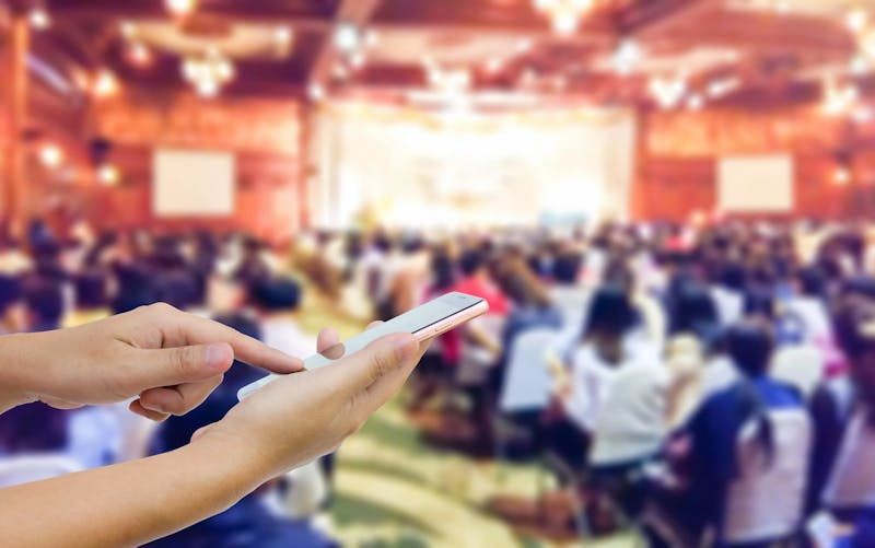 Close up of a mobile phone user in a busy conference event