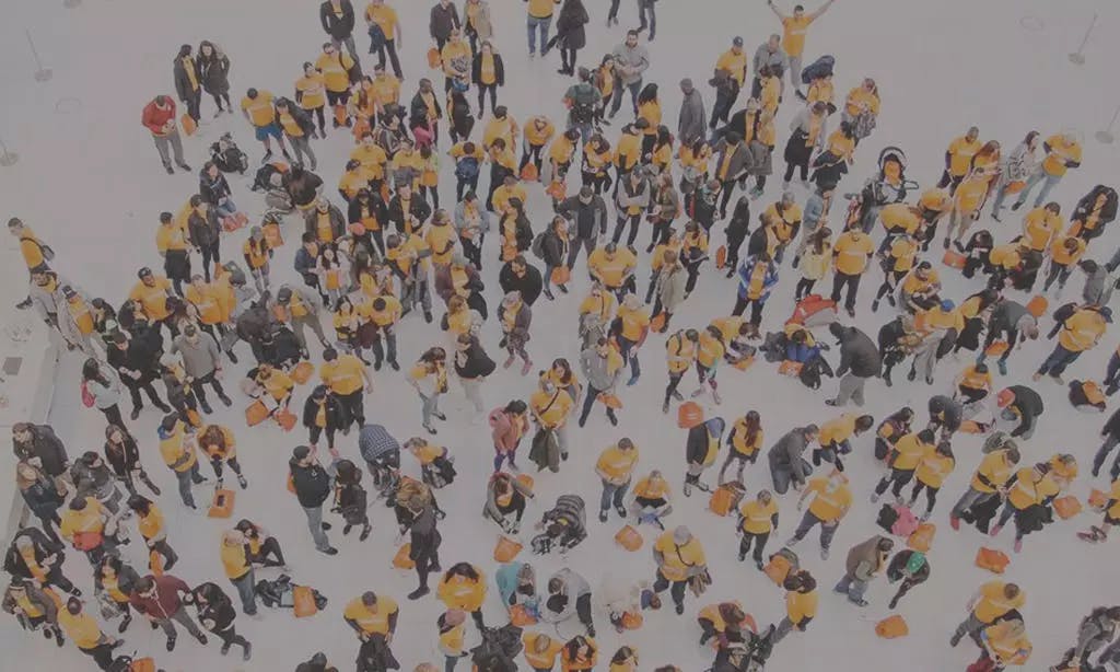 Crowd of people in yellow tshirts posing below for a photograph in Westfield Shopping Center