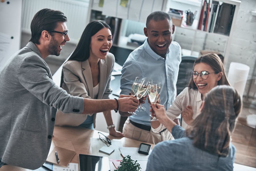 Young business people toasting each other and celebrating in an office. 