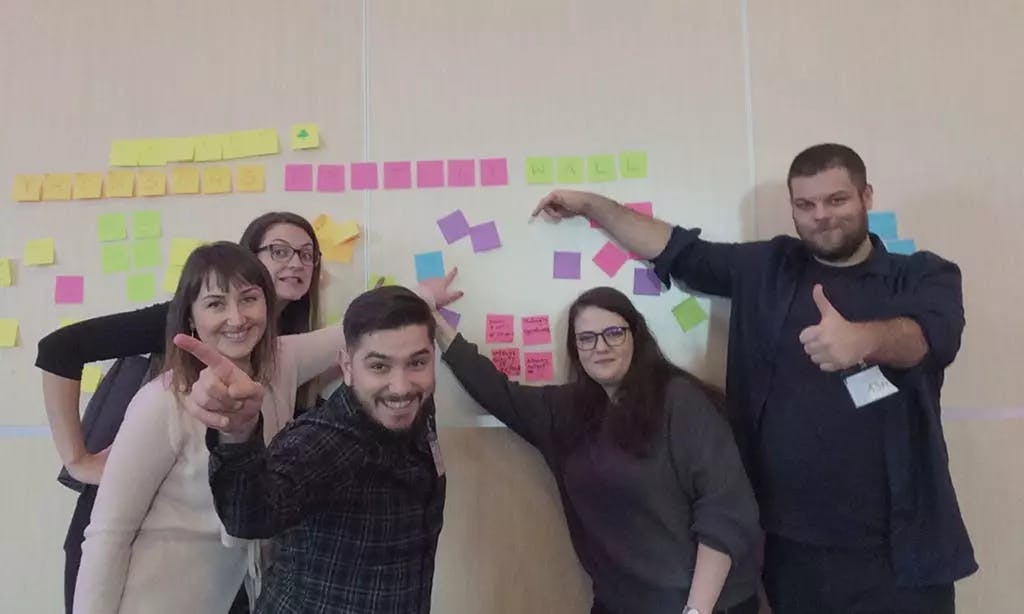Staff members pointing at a whiteboard covered in post it notes