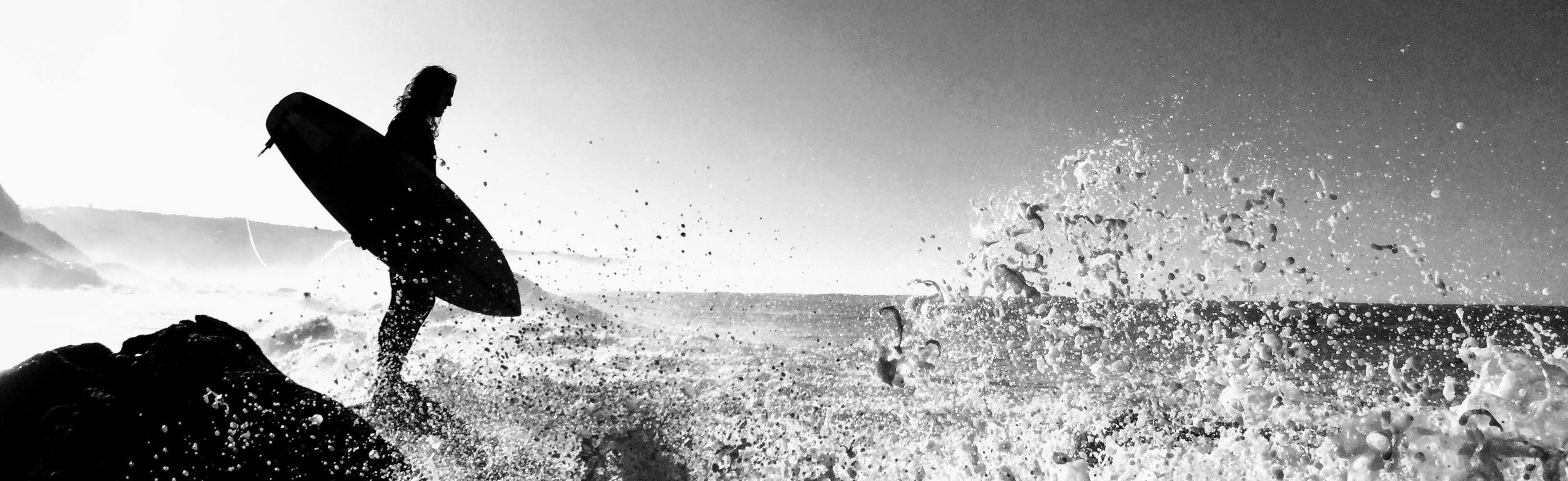 Silouetted person with a surfboard by the sea